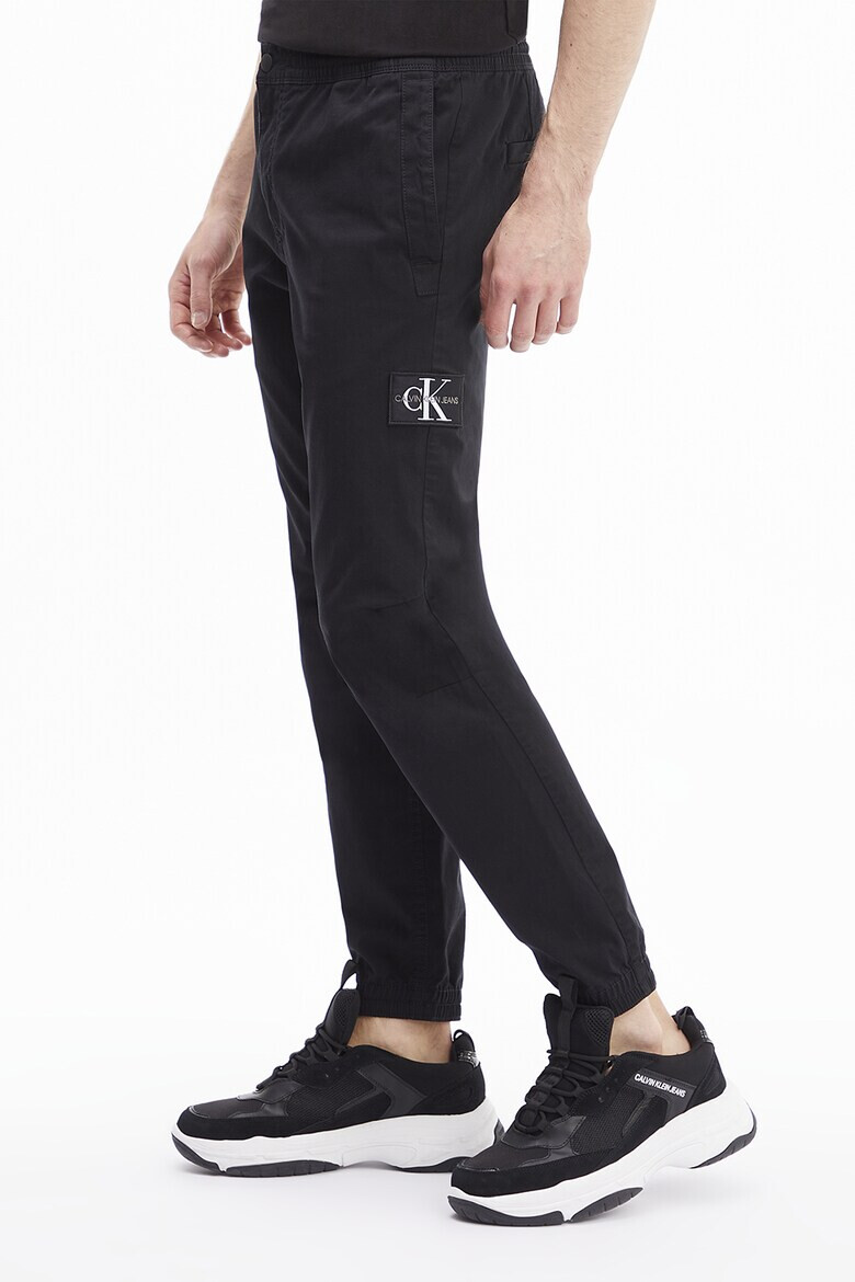 CALVIN KLEIN JEANS Pantaloni conici cu aplicatie logo - Pled.ro